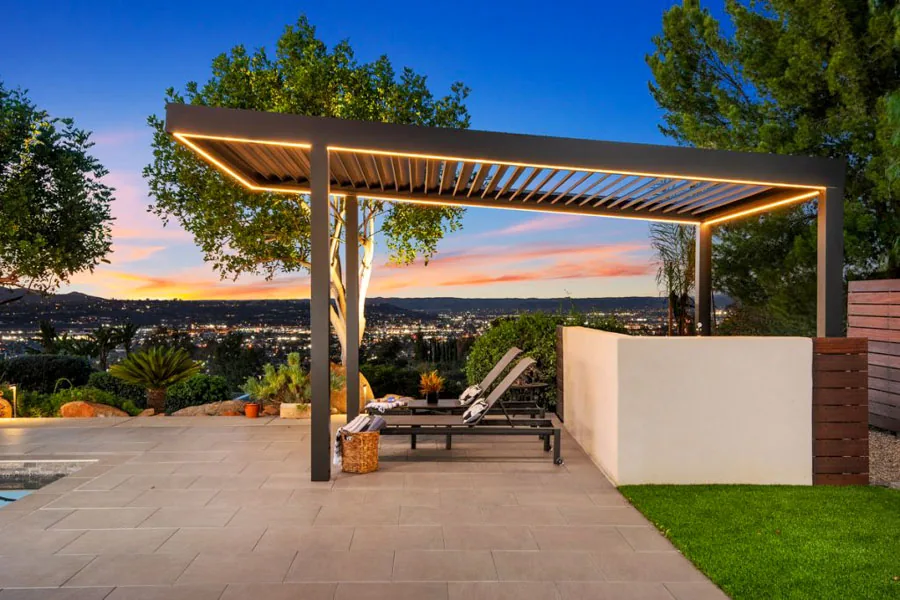 A modern patio cover featuring comfortable seating, warm ambient lighting, and stunning sunset views.