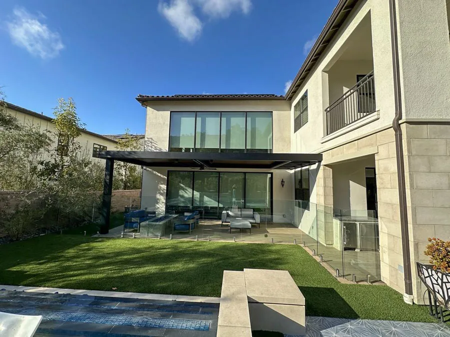 A modern backyard design with a covered lounge area, poolside seating, and elegant decor, creating an inviting outdoor space.