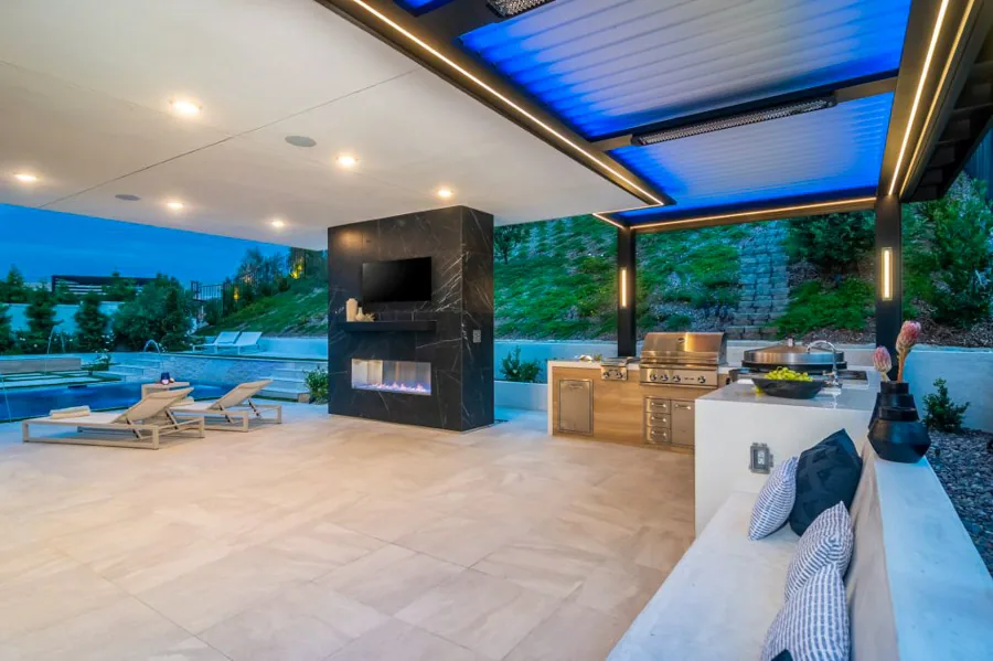 A sleek patio cover featuring a stylish outdoor kitchen, cozy fireplace, and warm ambient lighting, perfect for entertaining.